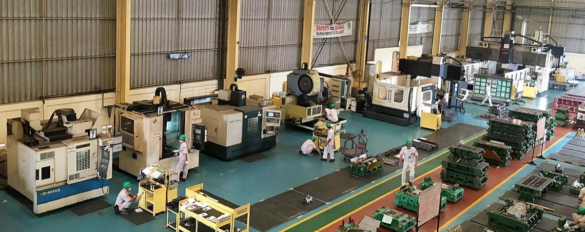 صالة تشغيل واسعة تصطفّ فيها ماكينات CNC ومراكز تفريز، ويعمل بينها فنّيون على أرضية المصنع